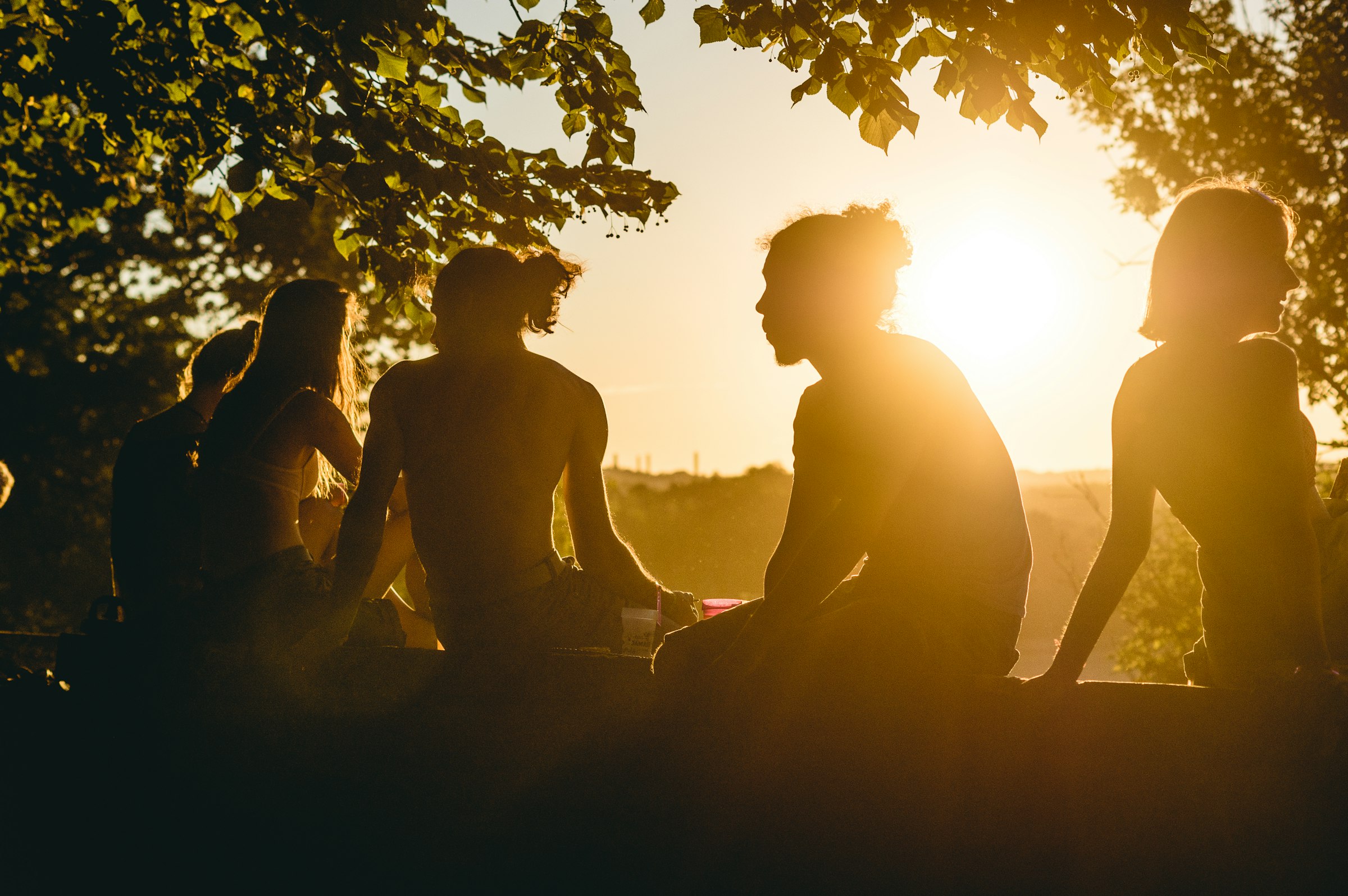 Friends sitting together on a hill at golden hour